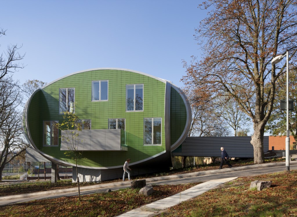 Green oval shaped building with floor to ceiling glazing 