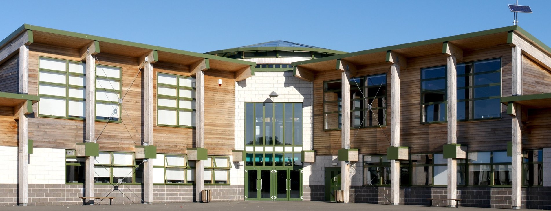 A school with a timber cladded design and windows in a green coloured frame