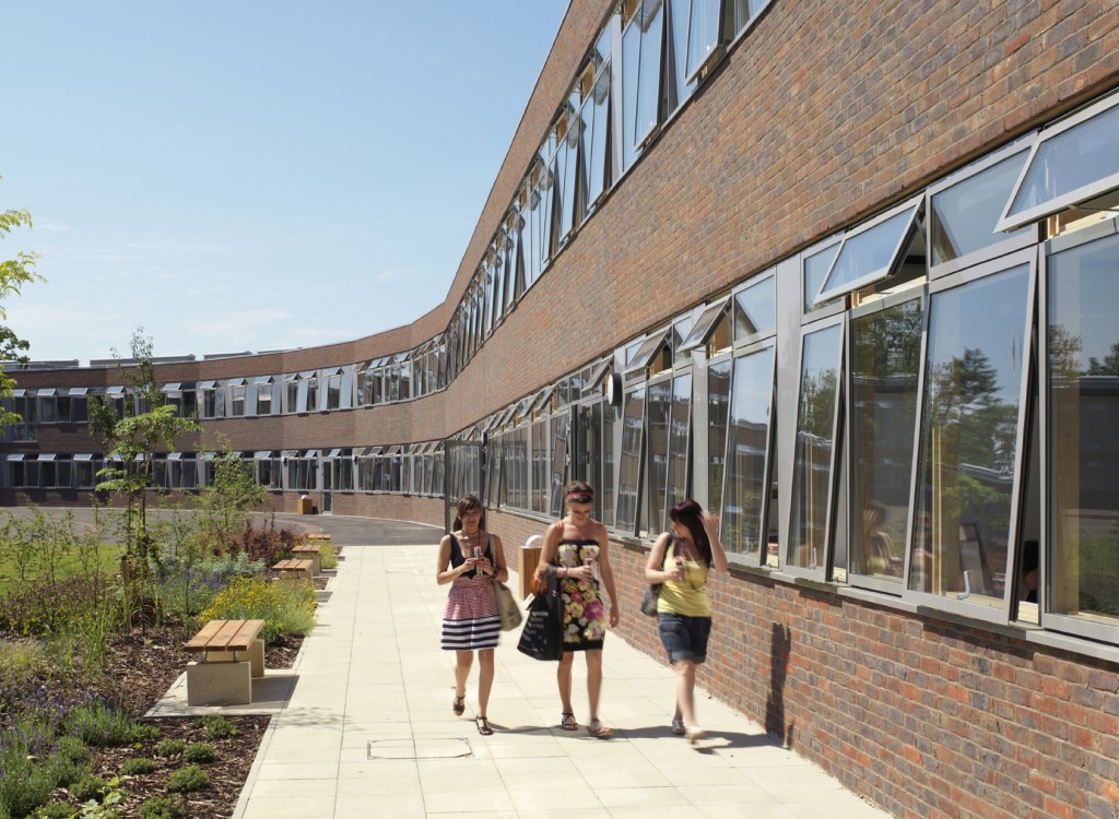 Three students walking outside a school with new glazing windows